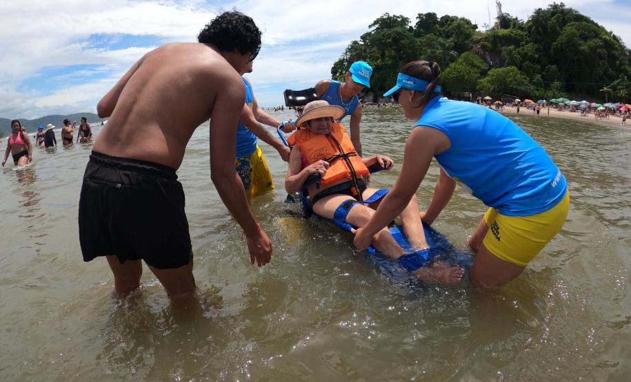 Mulher sendo conduzida na cadeira anfibia no mar.